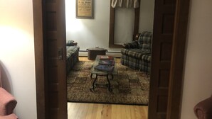 A living room with a sofa, armchair, and a coffee table. There is a framed notice on the wall and a window with curtains. - Lever Hill Lodge (Andover)