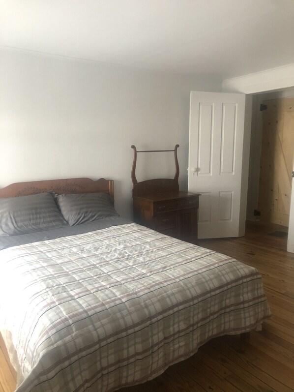 A bedroom with a bed, a wooden chair, and a white door.