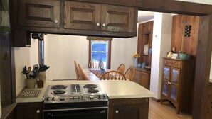 A kitchen with wooden cabinets, a stove, and a dining area with chairs. - Lever Hill Lodge (Andover)