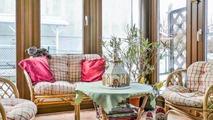 A cozy seating area with a wicker sofa, a small table with a decorative item, and a chair with a plaid cushion. - 2 bedroom stunning home in Brünlos (Brünlos)