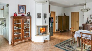 A cozy living room with a fireplace, wooden cabinets, and a dining area with a table and chairs. - 2 bedroom stunning home in Brünlos (Brünlos)