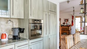 A modern kitchen with stainless steel appliances, a coffee maker, and a dining area with a wooden table and chairs. - 2 bedroom stunning home in Brünlos (Brünlos)