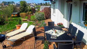 An outdoor patio with a table set for two, lounge chairs, and a barbecue grill. - 2 bedroom stunning home in Brünlos (Brünlos)