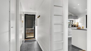 A modern kitchen with white cabinetry, a black countertop, and a visible coffee machine.