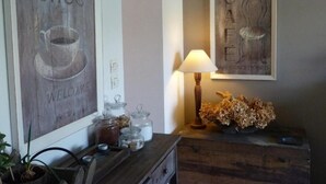 A cozy room with a wooden coffee sign, a lamp, and a decorative vase. - Les Persiennes (Saintes)