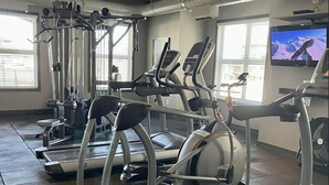 Et fitnesscenter med løbebånd, crosstrainere og træningsudstyr.
