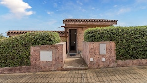 A building entrance with a tiled roof, a door, and two electrical boxes on the walls. - 2 bedroom awesome home in Villaputzu CA (Villaputzu CA)