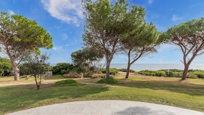 A landscaped outdoor area with a paved walkway, trees, and a view of the sea. - 2 bedroom awesome home in Villaputzu CA (Villaputzu CA)