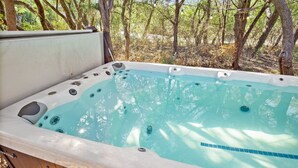 Un jacuzzi con cubierta de madera, rodeado de árboles.