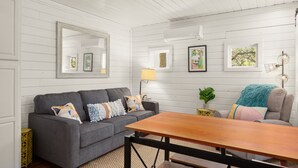 Un salón acogedor con un sofá gris, una mesa de centro de madera y un espejo grande en la pared.
