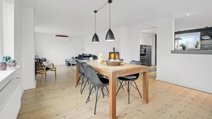 Una cocina moderna con una mesa de madera, sillas negras y lámparas colgantes.
