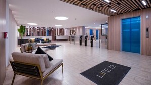 Um hall moderno com balcão de recepção, área de estar e elevador.