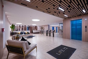 Eine moderne Lobby mit Empfangsschalter, Sitzbereich und Aufzug.