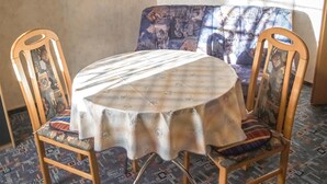 A round table with a floral tablecloth, two wooden chairs with cushioned seats, and a patterned sofa in the background. - Nice apartment in Rankwitz/ OT Suckow with sauna (Rankwitz/ OT Suckow)