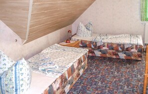 Una stanza accogliente e intima con due letti, soffitto in legno e biancheria a motivi decorativi.