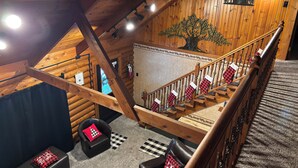 A wooden interior with a staircase, checkered stockings on the railing, and a wall-mounted tree decoration. - Cozy Perrysburg Cabins - Modern 2 Bedroom with Large Loft & Sleep#Bed! (Perrysburg)