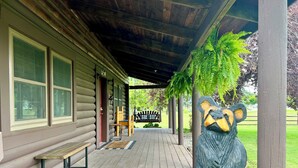 A log cabin with a porch, a bench, and a bear statue. - Cozy Perrysburg Cabins - Modern 2 Bedroom with Large Loft & Sleep#Bed! (Perrysburg)