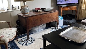 A living room with a wooden desk, a television, a lamp, and a patterned rug. - RIVERSIDE CHARACTER HOUSE WITH OUTBUILDING (Ménilles)