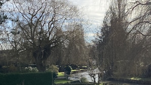 A well-maintained garden with a circular pond, neatly trimmed grass, and a variety of trees. - RIVERSIDE CHARACTER HOUSE WITH OUTBUILDING (Ménilles)