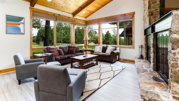 Un salón amplio con chimenea de piedra, ventanas grandes y ventilador de techo.