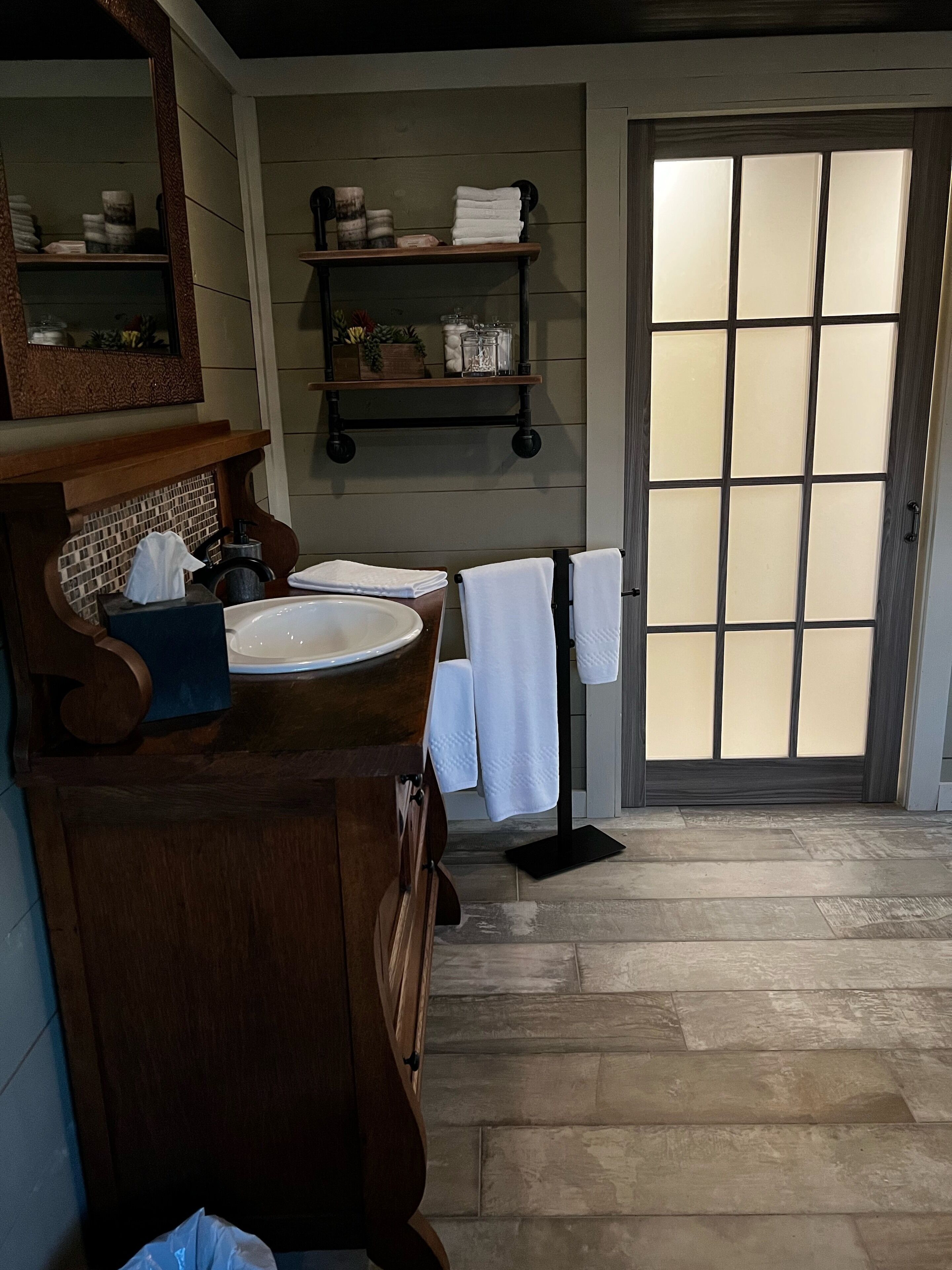 Une salle de bain avec deux lavabos, un miroir, une étagère avec des articles de toilette et un porte-serviettes.