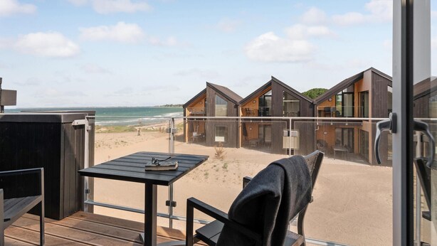 Un hôtel moderne situé en bord de mer, doté de plusieurs chalets en bois, d’une plage de sable et offrant une vue sur l’océan.