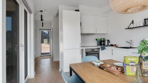 Une cuisine moderne avec des meubles blancs, une table à manger en bois et un luminaire suspendu.