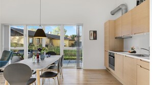 Eine moderne Küche mit Holzausstattung, einer Edelstahlspüle und einem großen Fenster mit Blick auf einen Garten.