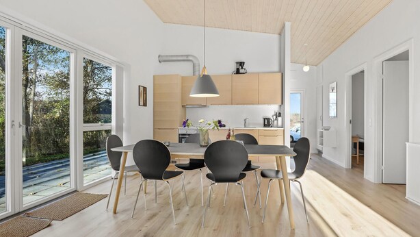Eine moderne Küche mit Holzschränken, einer zentralen Kochinsel und einem Essbereich mit Tisch und Stühlen.