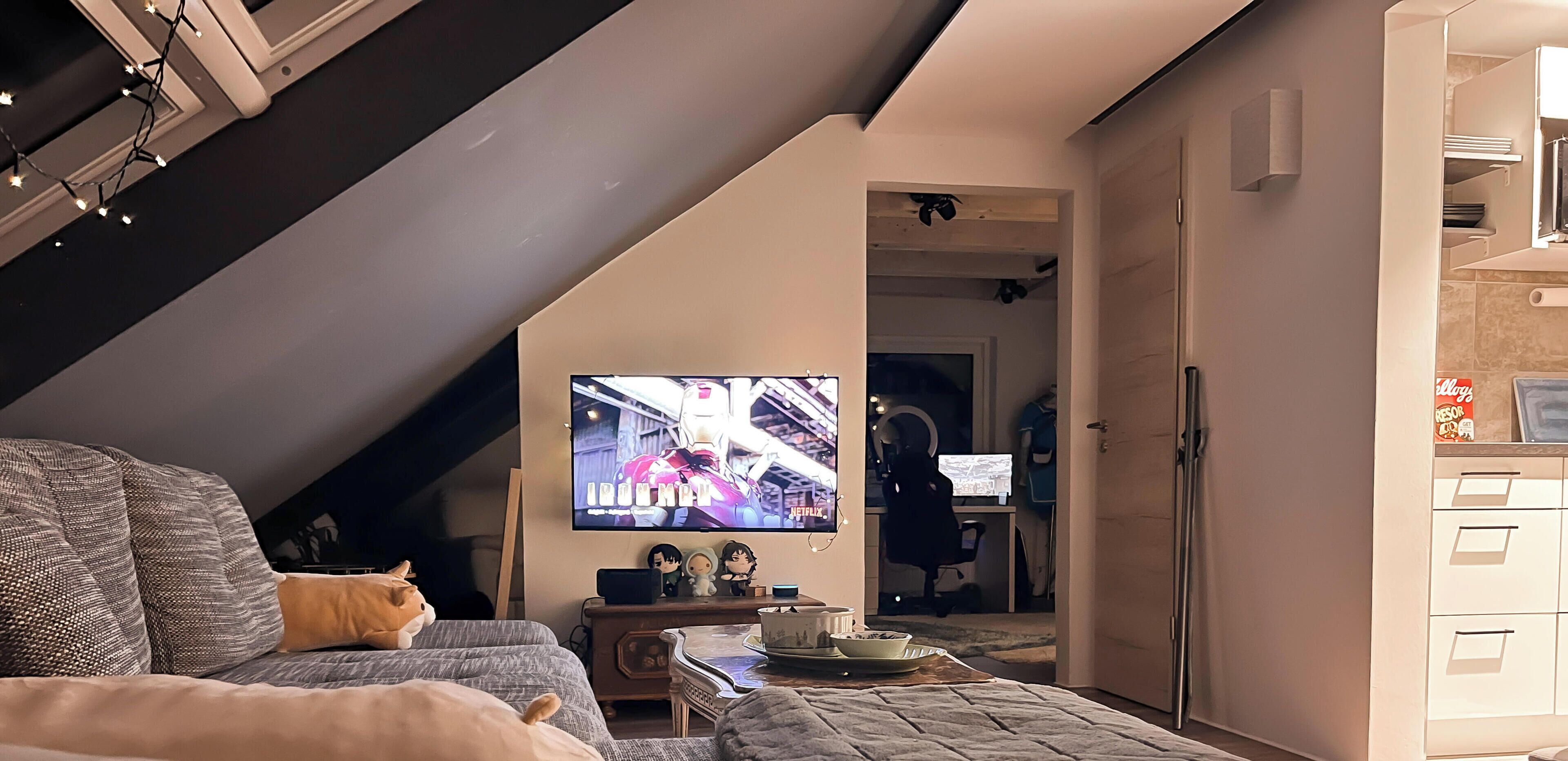 A cozy living room with a TV, a sofa, a cat, and a small table.