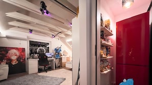 Una habitación moderna con una configuración para videojuegos, un refrigerador rojo y una zona de estar acogedora.