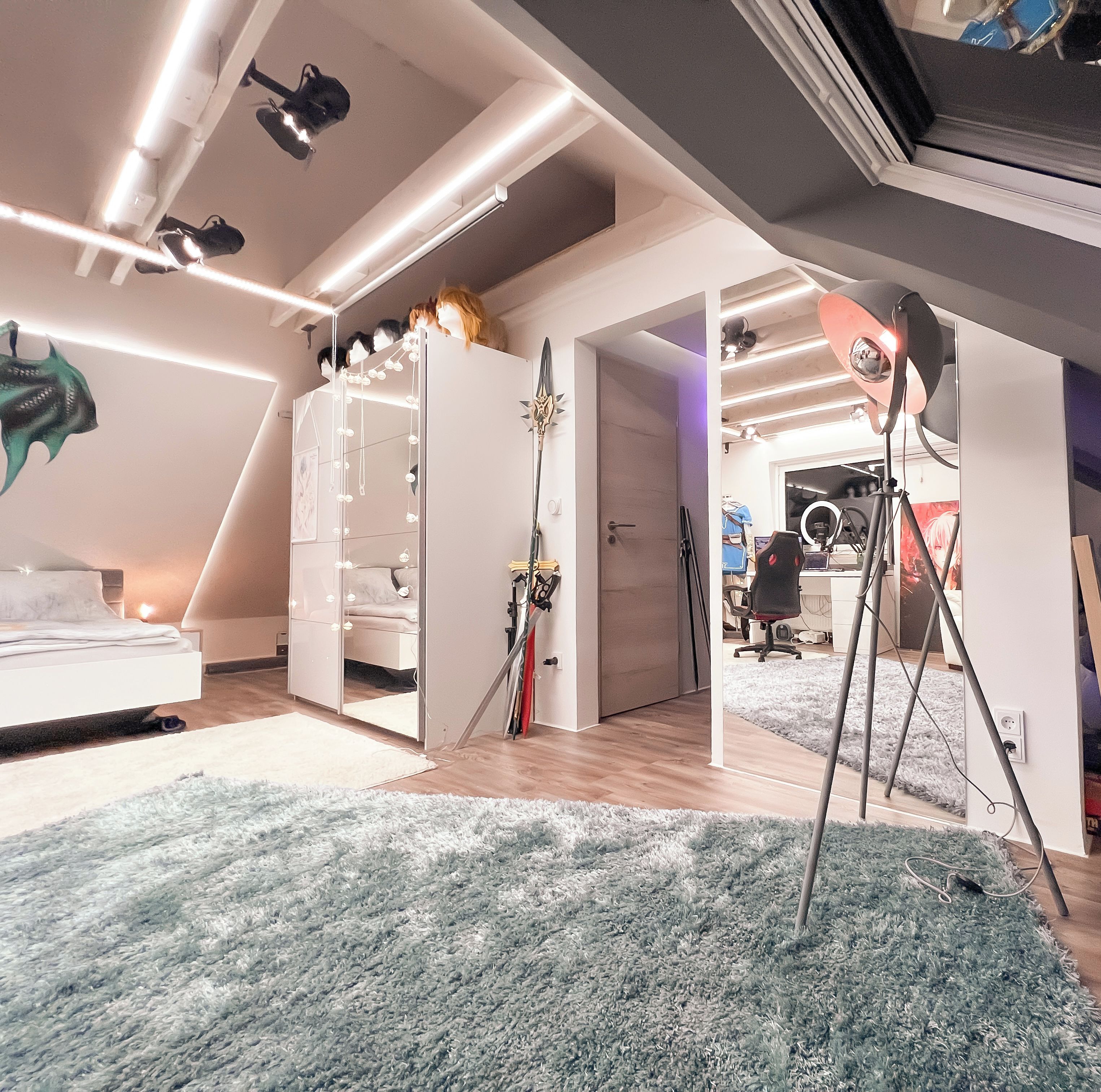 Ein modernes Schlafzimmer mit schrägverdeckter Decke, einem Bett, einem Kleiderschrank und einem Schreibtischbereich mit Computer und Gaming-Sessel.