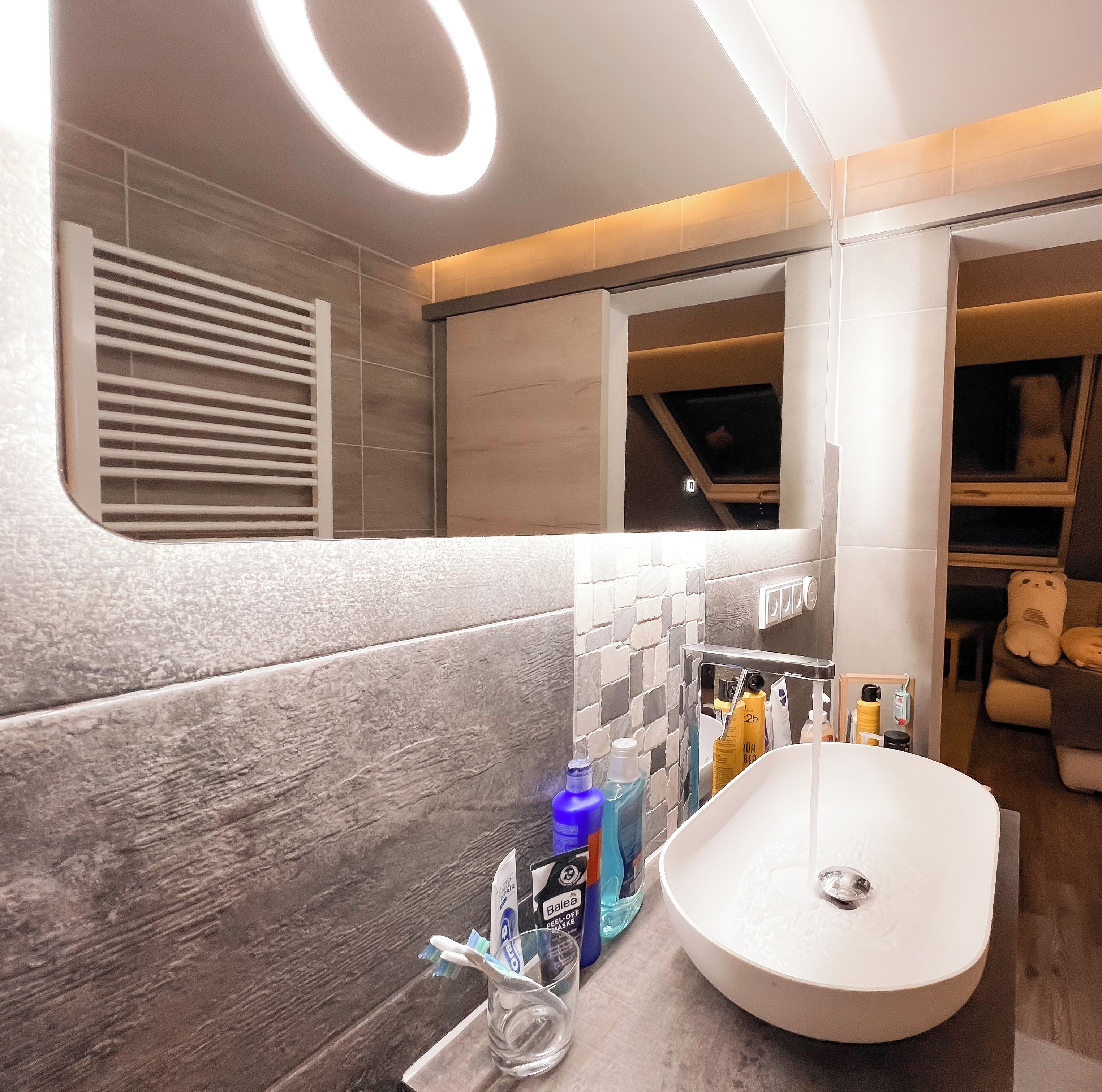 A modern bathroom with a large sink, toiletries, and a window.