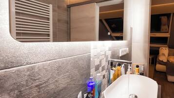 Un bagno moderno con un lavandino ampio, articoli da toilette e una finestra.