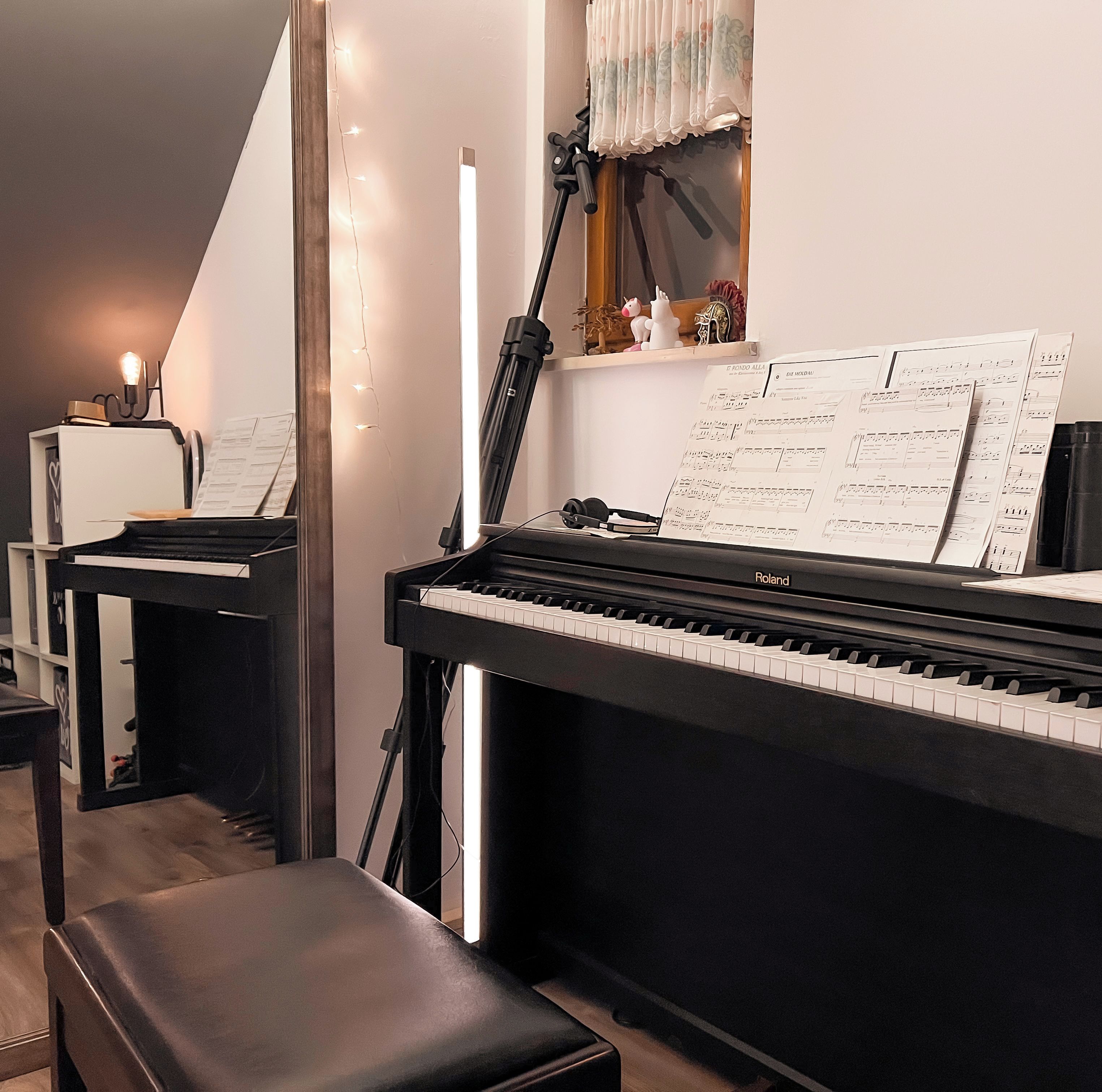 Un piano con partituras, un taburete y una pequeña mesa con un objeto decorativo.