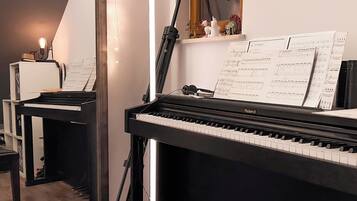 Un piano con partituras, un taburete y una pequeña mesa con un objeto decorativo.