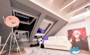 Uma sala de estar moderna com um sofá branco, uma janela grande, um bichinho de pelúcia de panda e um pôster na parede.