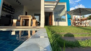 A modern house with a pool, outdoor furniture, and a clear sky. - Barra do Jacuípe - House with 3 bedrooms, 1 of which is a suite. (Jacuípe)