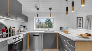 Ett modernt kök med en inbyggd diskmaskin, vitvaror i rostfritt stål och ett fönster med utsikt över omgivningen.