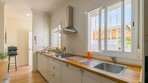 A modern kitchen with white cabinetry, a wooden countertop, a stainless steel sink, and a window with a view of the outside.