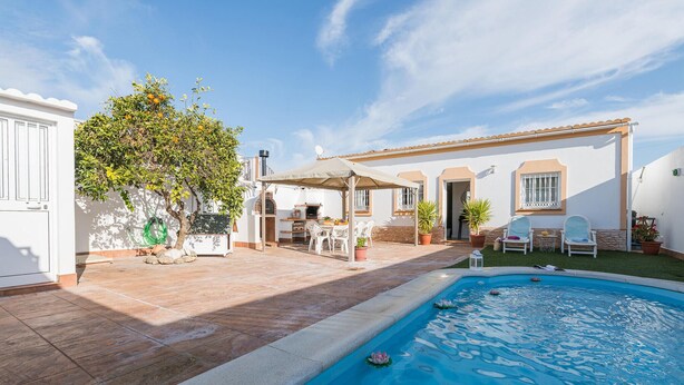 A poolside area with a covered seating area, a barbecue, and a small garden.