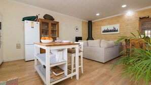 A compact living space with a kitchenette, a sofa, a dining table, and a decorative clock.