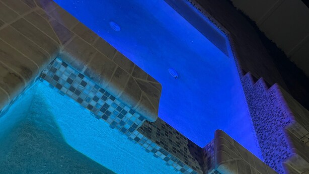 A swimming pool with a tiled edge and a blue light. - Gorgeous Heated Pool Home Built in 2020 with Jacuzzi- 5.3 mi from INTL Airport…  (Jacksonville)