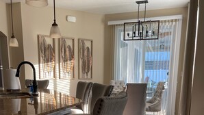 A modern dining area with a marble countertop, grey upholstered chairs, and a chandelier. - Gorgeous Heated Pool Home Built in 2020 with Jacuzzi- 5.3 mi from INTL Airport…  (Jacksonville)