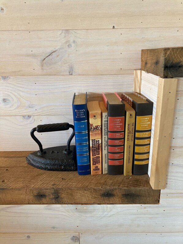 A wooden shelf with books and a black metal kettle.