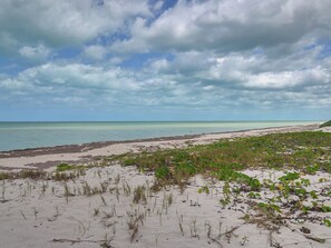 Una playa con cielos despejados y aguas tranquilas.