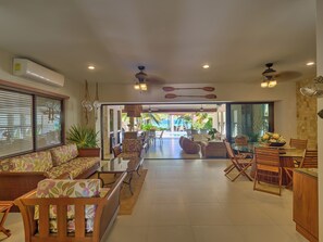 Un amplio espacio de estar con sofá, sillas, una mesa de comedor y vistas a la piscina.