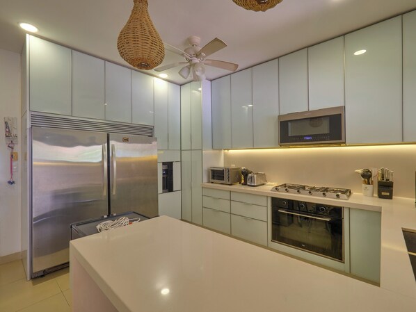 A modern kitchen with a large refrigerator, microwave, stove, and oven. - Casa Macabi - Yucatan Home Rentals (Chicxulub Puerto)