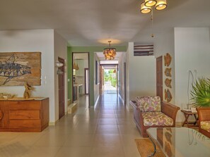 A spacious hallway with a wooden cabinet, a sofa, and a dining table. - Casa Macabi - Yucatan Home Rentals (Chicxulub Puerto)