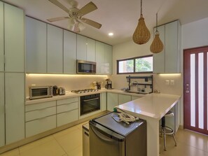 A modern kitchen with a central island, built-in appliances, and a ceiling fan. - Casa Macabi - Yucatan Home Rentals (Chicxulub Puerto)